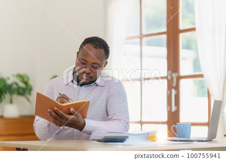 Smiling American African Banker or Accountant makes financial report and studies annual figures, analyzes profits. Accountant checks status of financial Smiling American African Banker or Accountant makes financial report and studies annual figures, analyzes profits. Accountant checks status of financial 100755941