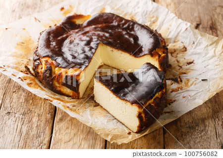Traditional basque burnt cheesecake on a rustic wooden table closeup. Horizontal Traditional basque burnt cheesecake on a rustic wooden table closeup. Horizontal 100756082