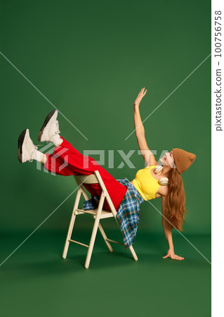 Full-length photo of cheerful girl wearing stylish clothes having fun over green background. Youth fashion 100756758