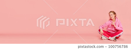 Banner of jolly young girl wearing sport clothes and smiling over pink background. Copy space for ad 100756786