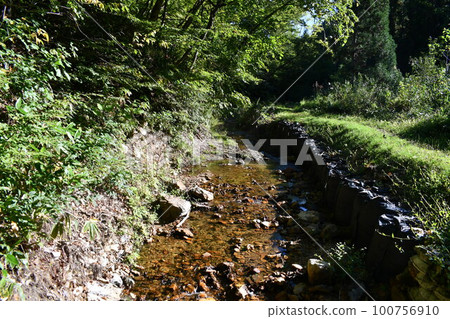 Scenery of a river behind a waterfall with a gentle stream in the sun Scenery of a river behind a waterfall with a gentle stream in the sun 100756910