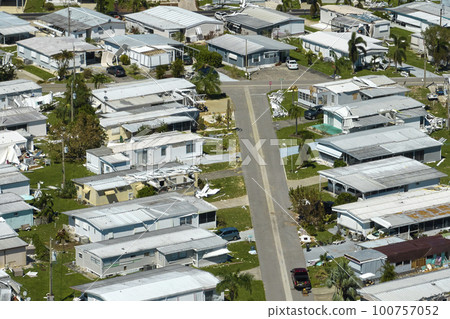 Severely damaged by hurricane Ian houses in Florida mobile home residential area. Consequences of natural disaster 100757052