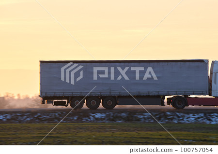 Semi-truck with cargo trailer driving on highway hauling goods in evening. Delivery transportation and logistics concept 100757054