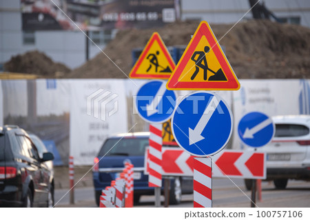 Roadworks warning traffic signs of construction work on city street and slowly moving cars 100757106