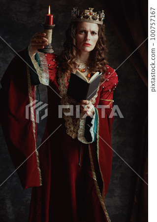 Full length portrait of medieval queen in red dress with book 100757167