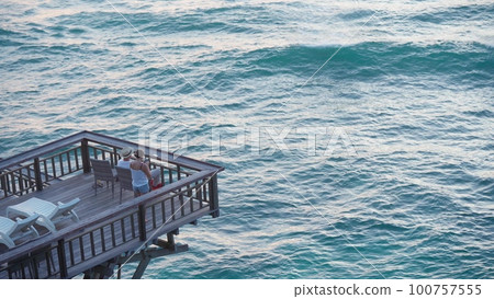 Silhouette of a young couple filming a sunset on a terrace by the sea or ocean on a mobile phone Silhouette of a young couple filming a sunset on a terrace by the sea or ocean on a mobile phone 100757555