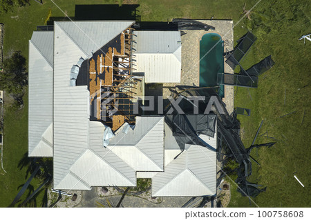 Hurricane Ian destroyed house roof in Florida residential area. Natural disaster and its consequences 100758608
