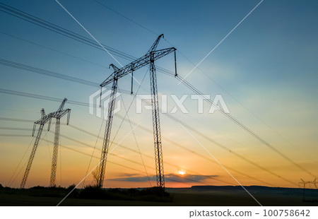 High voltage towers with electric power lines at sunset. 100758642