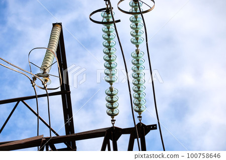 High voltage tower with electric power lines divided by safe guard bushing transfening safely electrical energy through cable wires. Electricity transmission on long distance concept 100758646