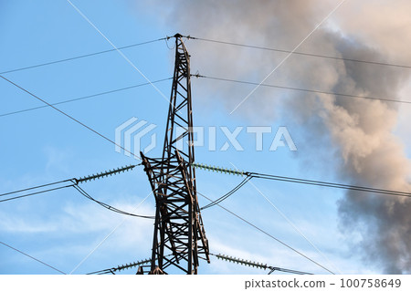 High voltage electric pylons against coal power plant high pipes with black smoke moving upwards polluting atmosphere. Production of electrical energy with fossil fuel concept 100758649