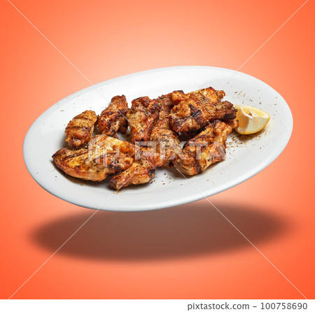 Floating White plate with roasted chicken wings Floating White plate with roasted chicken wings 100758690
