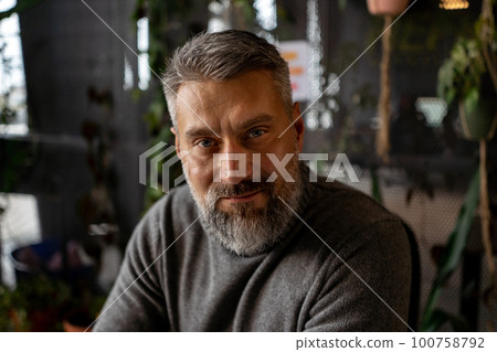 Portrait view of the attractive senior guy is posing to the camera at green plants office Portrait view of the attractive senior guy is posing to the camera at green plants office 100758792
