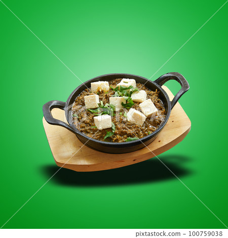 Floating Palak paneer baked in little pan on green Floating Palak paneer baked in little pan on green 100759038