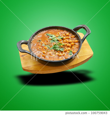 Floating chana masala in little pan on green 100759043