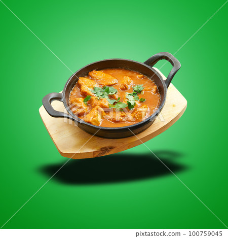 Floating Chicken curry baked in little pan on green 100759045