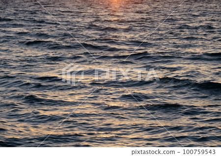 Dramatic bright red sky at ocean sunset, soft evening clouds over sea dark water 100759543