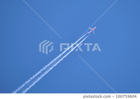 Distant passenger jet plane flying on high altitude on clear blue sky leaving white smoke trace of contrail behind. Air transportation concept 100759604