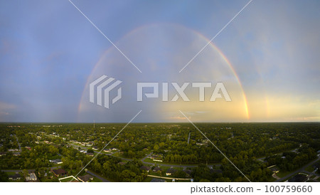 Colorful round rainbow over rural town suburbs against blue evening sky after heavy thunderstorm 100759660