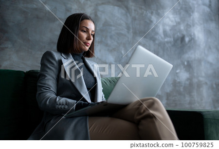 Young female manager sitting on green sofa in loft living room. Young female manager sitting on green sofa in loft living room. 100759825