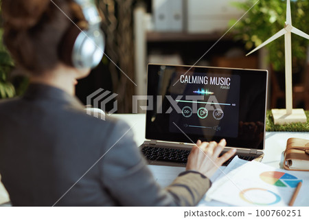 Seen from behind business woman listening to music Seen from behind business woman listening to music 100760251