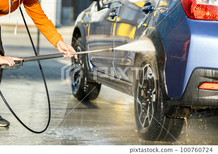 Closeup of male driver washing his car with contactless high pressure water jet in self service car wash. Closeup of male driver washing his car with contactless high pressure water jet in self service car wash. 100760724