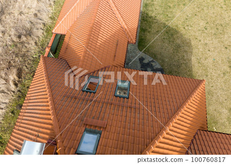Closeup of attic windows on house roof top covered with ceramic shingles. Tiled covering of building Closeup of attic windows on house roof top covered with ceramic shingles. Tiled covering of building 100760817