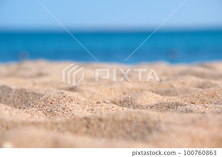 Close up of clean yellow sand surface covering seaside beach with blue sea water on background. Travel and vacations concept. 100760863
