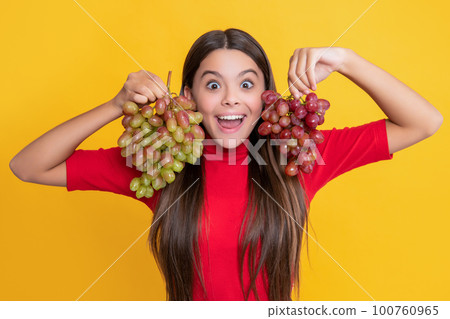 amazed positive girl hold bunch of grapes on yellow background amazed positive girl hold bunch of grapes on yellow background 100760965
