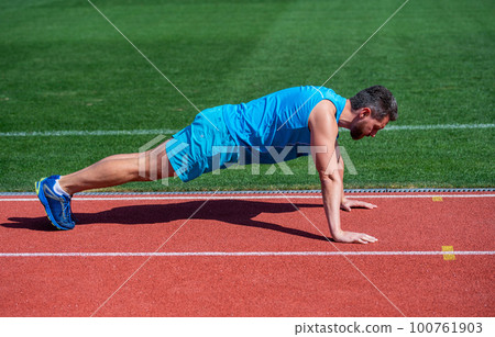 male strength and power. sportsman in plank. athlete do pushups. train his core muscles. man doing push ups exercise on stadium. fitness gym outdoor. Working his core muscles male strength and power. sportsman in plank. athlete do pushups. train his core muscles. man doing push ups exercise on stadium. fitness gym outdoor. Working his core muscles 100761903