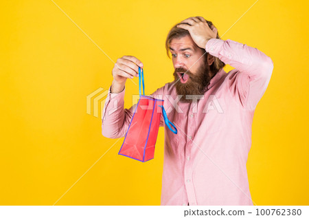 mature man with beard and trendy hairstyle hold gift package, shopper 100762380