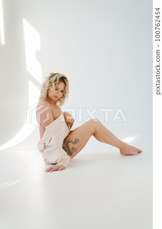 a gentle naked blonde woman in a white shirt on the floor.  100762454