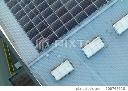 Aerial view of solar power plant with blue photovoltaic panels mounted on industrial building roof for producing green ecological electricity. Production of sustainable energy concept 100762618