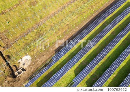 Aerial view of solar power plant under construction on green field. Assembling of electric panels for producing clean ecologic energy. 100762622