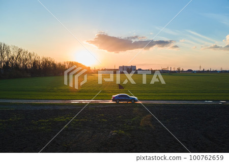 Aerial view of sedan car driving fast on dirt road at sunset. Traveling by vehicle concept. Aerial view of sedan car driving fast on dirt road at sunset. Traveling by vehicle concept. 100762659
