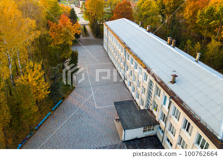 Aerial view of school, college or kindergarten building with big yard among autumn trees on rural landscape background 100762664