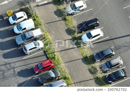 Aerial view of many colorful cars parked on parking lot with lines and markings for parking places and directions 100762782