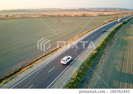 Aerial view of intercity road with fast driving cars at sunset. Top view from drone of highway traffic in evening Aerial view of intercity road with fast driving cars at sunset. Top view from drone of highway traffic in evening 100762843