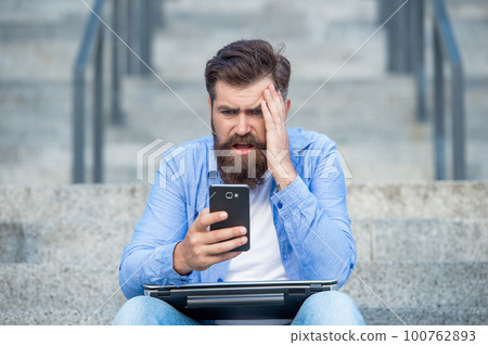 Disappointed guy lost bet. Upset guy checking up betting results in mobile phone. Making bet Disappointed guy lost bet. Upset guy checking up betting results in mobile phone. Making bet 100762893