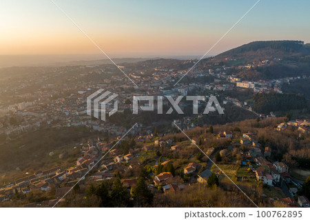 Aerial view of dense historic center of Thiers town in Puy-de-Dome department, Auvergne-Rhone-Alpes region in France. Rooftops of old buildings and narrow streets at sunset 100762895