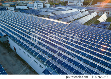 Aerial view of blue photovoltaic solar panels mounted on industrial building roof for producing green ecological electricity. Production of sustainable energy concept 100763065