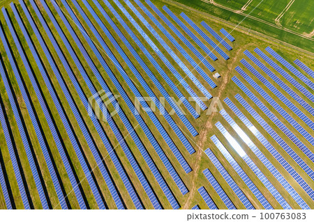 Aerial view of big sustainable electric power plant with many rows of solar photovoltaic panels for producing clean ecological electrical energy. Renewable electricity with zero emission concept. Aerial view of big sustainable electric power plant with many rows of solar photovoltaic panels for producing clean ecological electrical energy. Renewable electricity with zero emission concept. 100763083