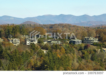Aerial view of big family houses on mountain top between yellow trees in North Carolina suburban area in fall season. Real estate development in american suburbs Aerial view of big family houses on mountain top between yellow trees in North Carolina suburban area in fall season. Real estate development in american suburbs 100763097