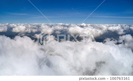 Aerial view from airplane window at high altitude of earth covered with puffy cumulus clouds forming before rainstorm. Aerial view from airplane window at high altitude of earth covered with puffy cumulus clouds forming before rainstorm. 100763161