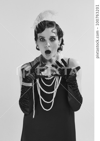 Closeup of beautifully dressed woman wearing old-time clothes standing and looking with scared face at camera over white background. Monochrome Closeup of beautifully dressed woman wearing old-time clothes standing and looking with scared face at camera over white background. Monochrome 100763201