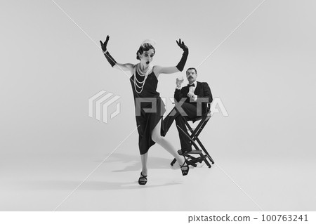 Emotional couple in love wearing old-time evening fancy outfits entertaining together. Monochrome. Eras comparison concept Emotional couple in love wearing old-time evening fancy outfits entertaining together. Monochrome. Eras comparison concept 100763241