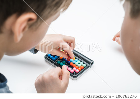 Close up rearview of boys play educational, strategy board game with black field and colorful balls. Therapy with games 100763270