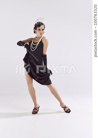 Photo of charming woman wearing chic vintage clothes dancing and looking at camera over white background Photo of charming woman wearing chic vintage clothes dancing and looking at camera over white background 100763320