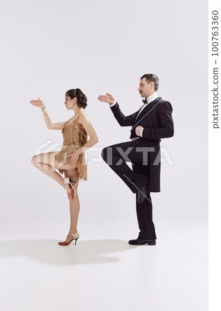 Chic couple of dancers in old-time evening costume dancing retro funny dance over white background. Love and music, vintage fashion concept 100763360