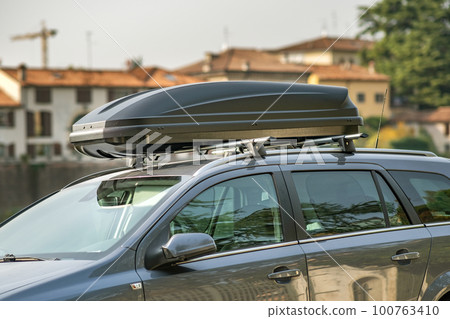 A car with roof baggage trunk parked on the side of the street on a parking lot. A car with roof baggage trunk parked on the side of the street on a parking lot. 100763410