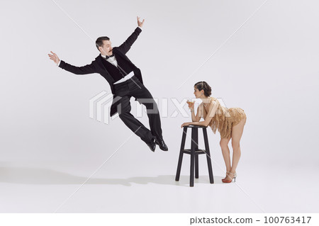 Retro man and beautiful woman in old-time evening chic outfits having fun over white background. Music, eras comparison, american culture concept 100763417